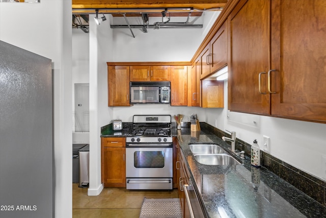 kitchen with gas stove, light tile patterned flooring, sink, and dark stone counters