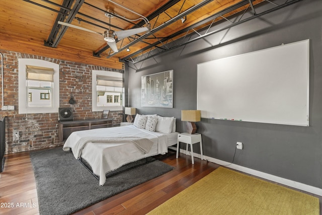 bedroom with a high ceiling, dark hardwood / wood-style floors, and brick wall