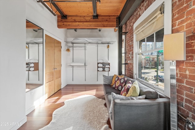 interior space featuring wood-type flooring, wood ceiling, and brick wall