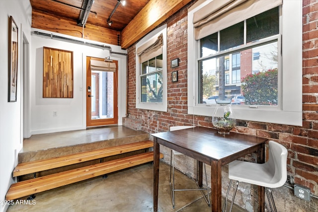 interior space featuring concrete floors, beamed ceiling, wooden ceiling, and brick wall