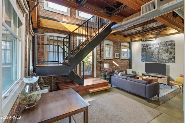 living room with a high ceiling, concrete floors, and brick wall