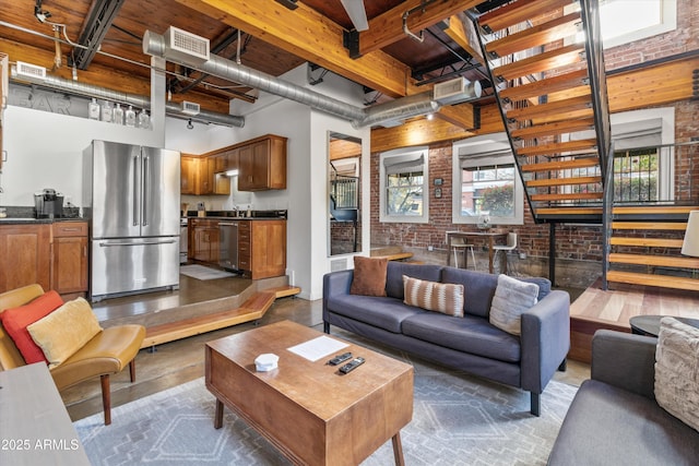 living room with beamed ceiling, a towering ceiling, and brick wall