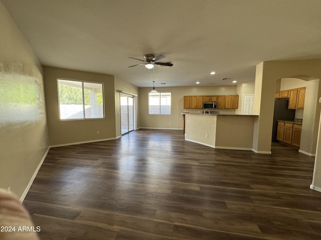 unfurnished living room featuring ceiling fan and dark wood-type flooring