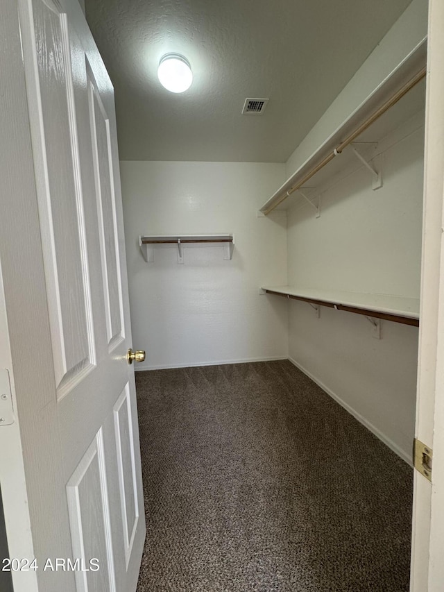 spacious closet featuring dark carpet