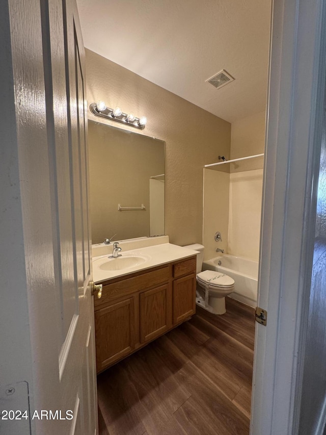 full bathroom featuring hardwood / wood-style flooring, vanity,  shower combination, and toilet