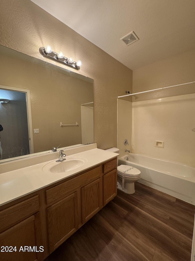 full bathroom featuring hardwood / wood-style flooring, vanity, shower / bathtub combination, and toilet