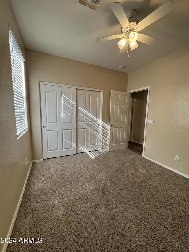 unfurnished bedroom with ceiling fan, a closet, and carpet floors