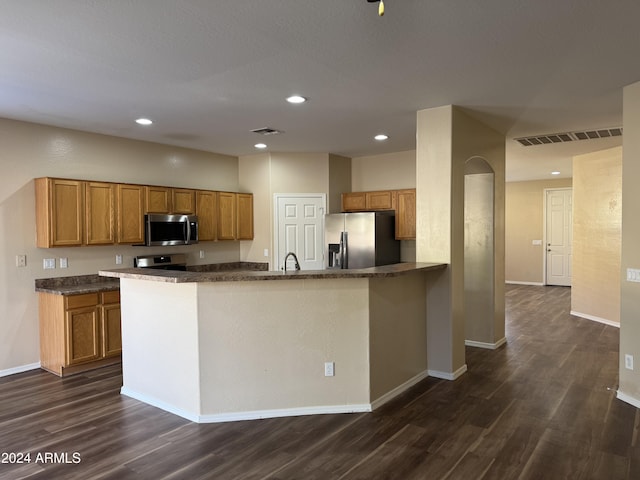 kitchen featuring kitchen peninsula, sink, dark hardwood / wood-style floors, and appliances with stainless steel finishes