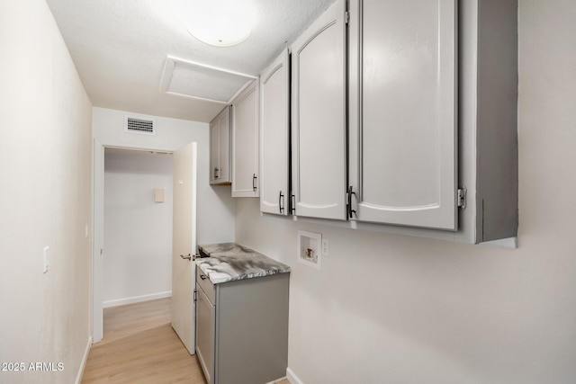 washroom with visible vents, cabinet space, light wood-style floors, attic access, and hookup for a washing machine