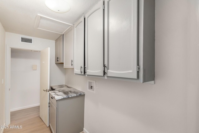 clothes washing area featuring light wood finished floors, visible vents, attic access, hookup for a washing machine, and cabinet space