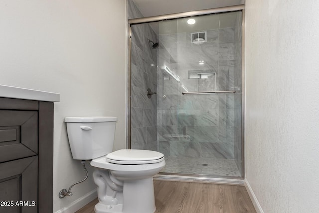 bathroom with baseboards, toilet, wood finished floors, and a shower stall