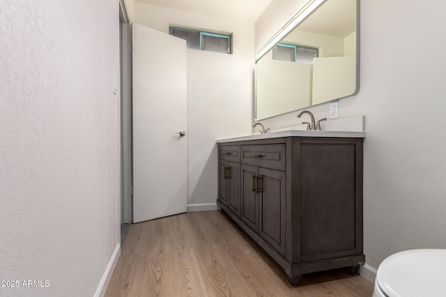 bathroom with vanity, wood finished floors, and baseboards