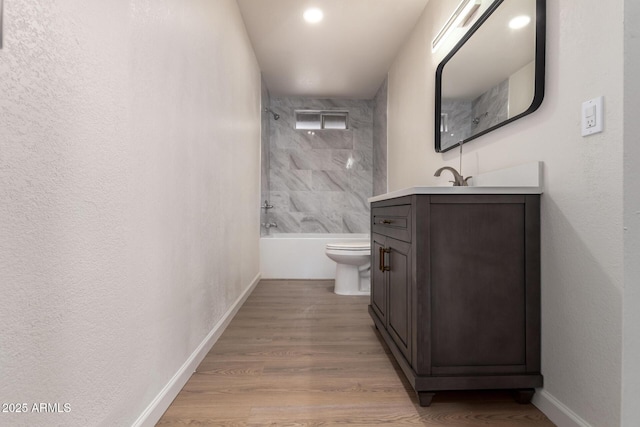 bathroom with toilet, wood finished floors, baseboards, bathing tub / shower combination, and vanity