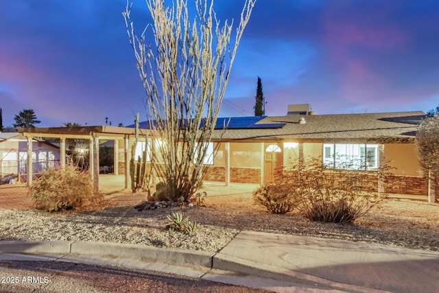 single story home featuring solar panels and stucco siding