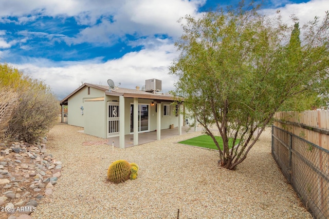 rear view of property with a patio area, central air condition unit, stucco siding, and fence