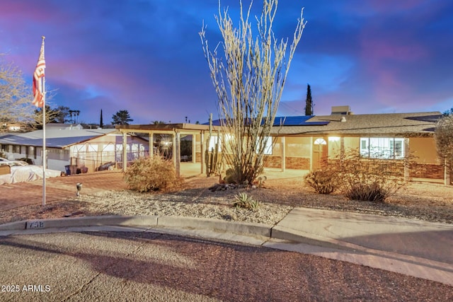 ranch-style home featuring roof mounted solar panels and stucco siding