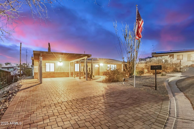 exterior space featuring brick siding, fence, decorative driveway, a patio area, and a pergola