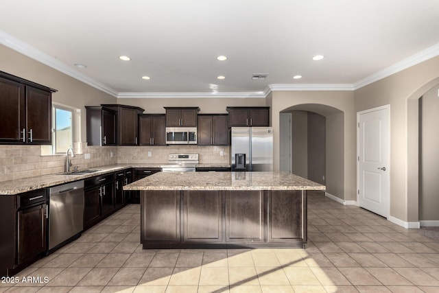 23789 W Chipman Rd, Buckeye, AZ 85326 - kitchen featuring arched walkways, a center island, a sink, and appliances with stainless steel finishes