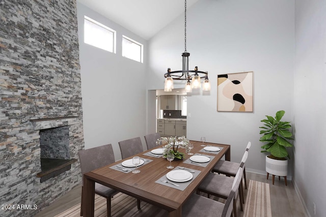 dining room with a fireplace, hardwood / wood-style floors, high vaulted ceiling, and an inviting chandelier