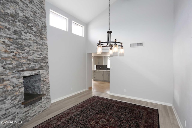 7331 E Valley Vista Dr, Scottsdale, AZ 85250 - unfurnished living room featuring a chandelier, light wood-type flooring, high vaulted ceiling, a fireplace, and baseboards