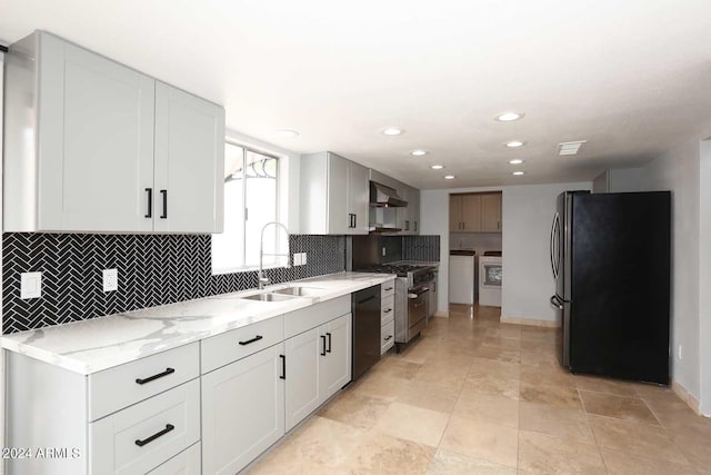 kitchen with stainless steel appliances, wall chimney range hood, sink, separate washer and dryer, and white cabinetry