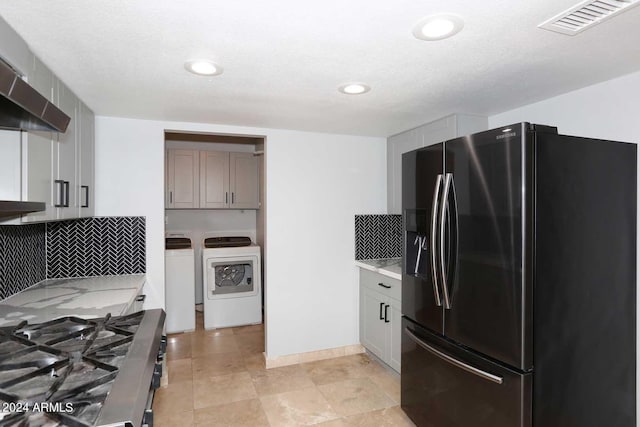 kitchen with stainless steel refrigerator with ice dispenser, gray cabinets, washing machine and dryer, range hood, and tasteful backsplash