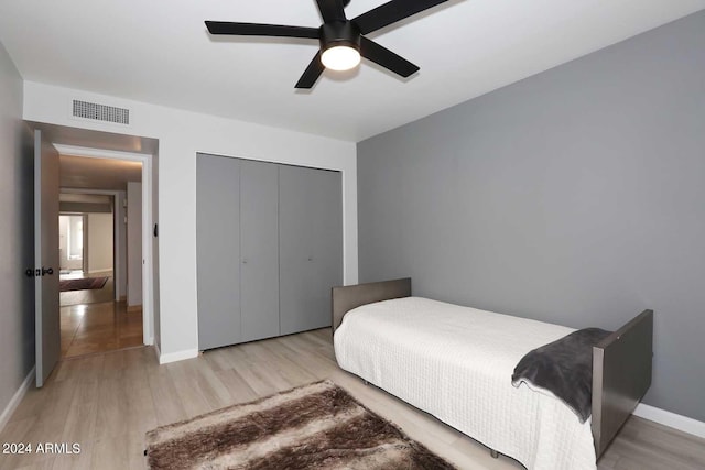 bedroom with ceiling fan, light hardwood / wood-style floors, and a closet