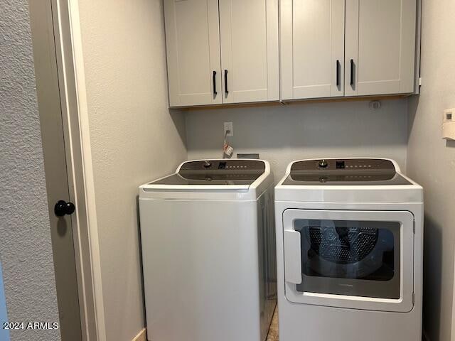 clothes washing area featuring washer and dryer and cabinets