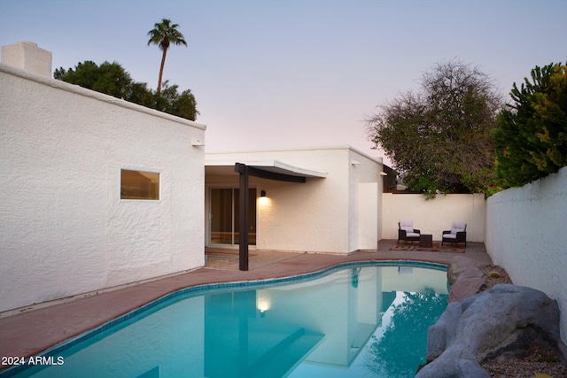 pool at dusk featuring a patio