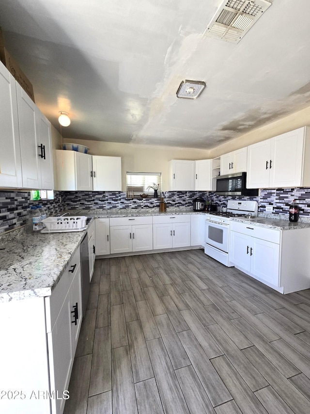 kitchen featuring appliances with stainless steel finishes, white cabinets, visible vents, and light stone counters