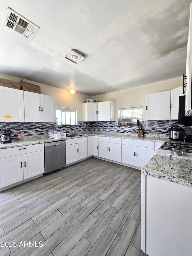 kitchen featuring visible vents, stainless steel dishwasher, and white cabinetry