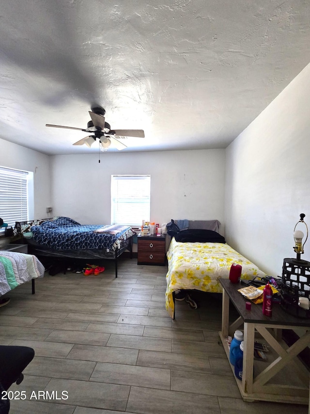 bedroom with ceiling fan, a textured ceiling, and wood finish floors