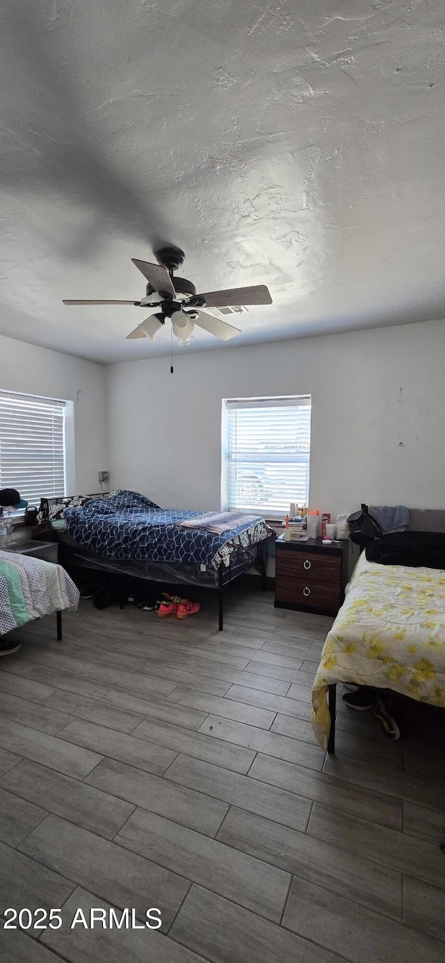 bedroom with a textured ceiling, ceiling fan, and light wood-type flooring