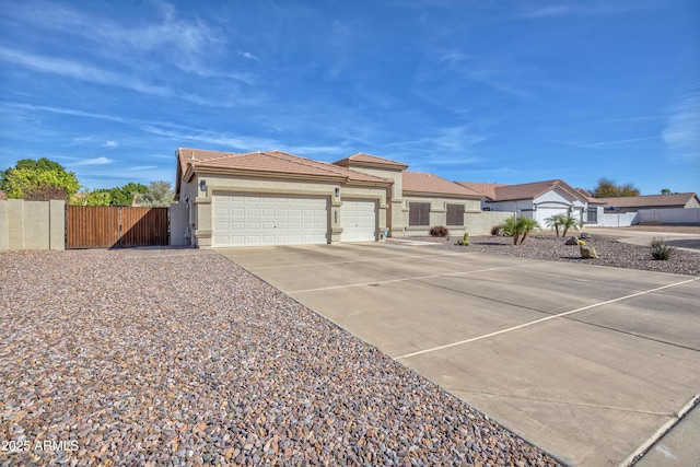 view of front of property with a gate, fence, driveway, an attached garage, and a tiled roof