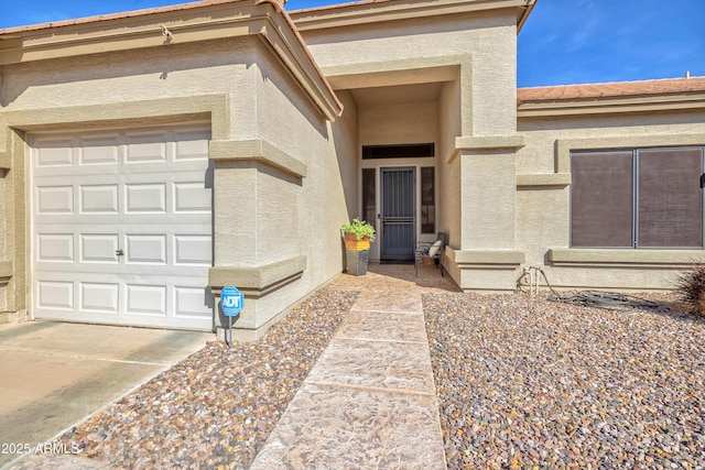 view of exterior entry with stucco siding, concrete driveway, and a garage