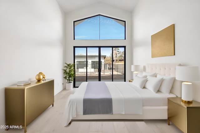 bedroom featuring light wood finished floors, high vaulted ceiling, and access to outside