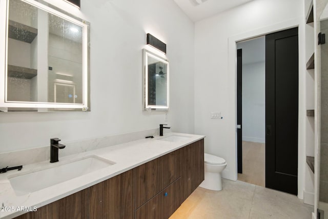 full bath with a sink, toilet, double vanity, and tile patterned floors