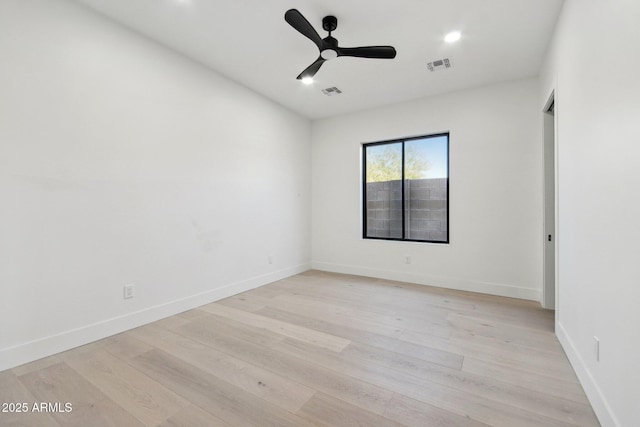 spare room with a ceiling fan, visible vents, light wood-style floors, and baseboards