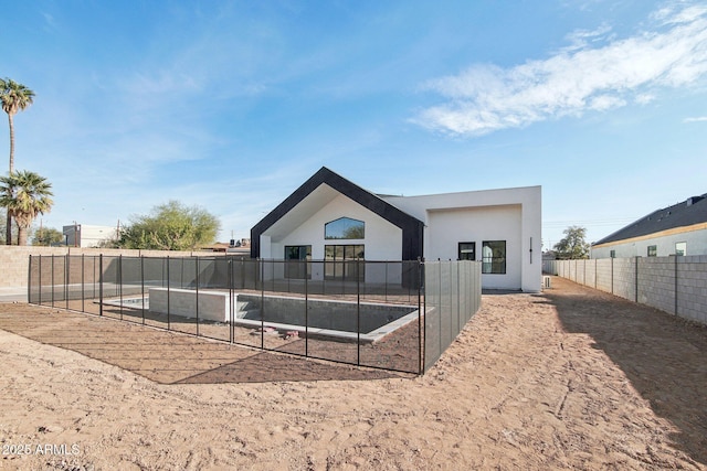 rear view of house with stucco siding and fence private yard