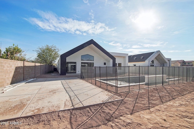 rear view of property featuring stucco siding, a fenced backyard, and a patio area