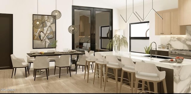 kitchen with a sink, light brown cabinets, pendant lighting, and light countertops