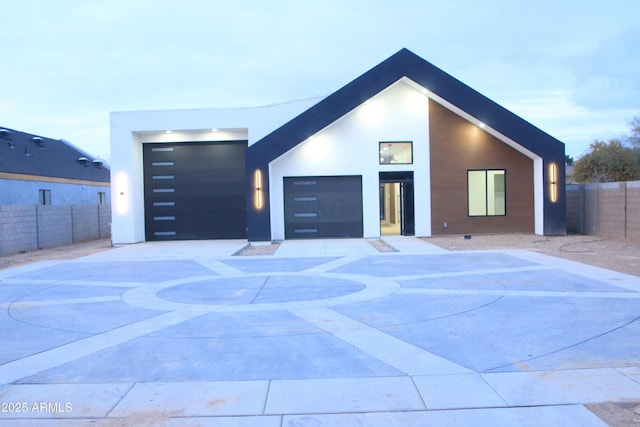 contemporary house featuring fence, stucco siding, driveway, and a garage