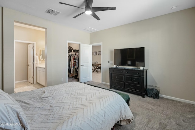 bedroom with ceiling fan, a spacious closet, connected bathroom, light colored carpet, and a closet