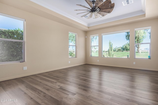 empty room with a tray ceiling, ceiling fan, and dark hardwood / wood-style floors