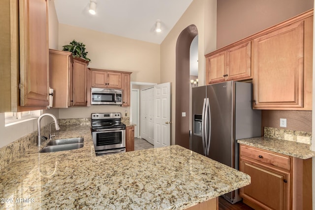 2753 E Kenwood St, Mesa, AZ 85213 - kitchen featuring a peninsula, light stone countertops, stainless steel appliances, arched walkways, and a sink