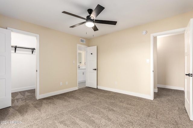 unfurnished bedroom with carpet flooring, a closet, a spacious closet, and ceiling fan