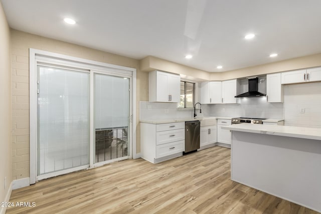 kitchen featuring white cabinets, light wood-type flooring, wall chimney range hood, and appliances with stainless steel finishes