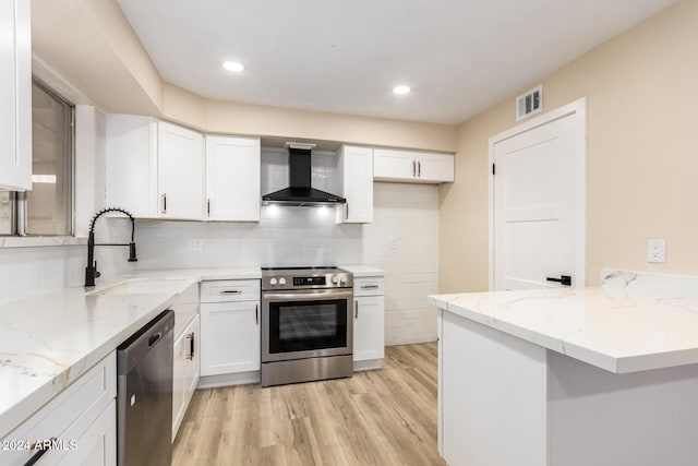 kitchen with sink, wall chimney exhaust hood, stainless steel appliances, light hardwood / wood-style floors, and white cabinets