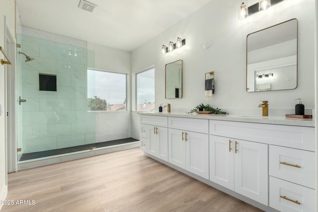 bathroom featuring vanity, wood-type flooring, and a tile shower