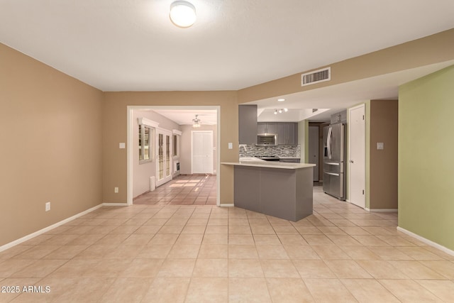 kitchen featuring decorative backsplash, light tile patterned floors, kitchen peninsula, and appliances with stainless steel finishes